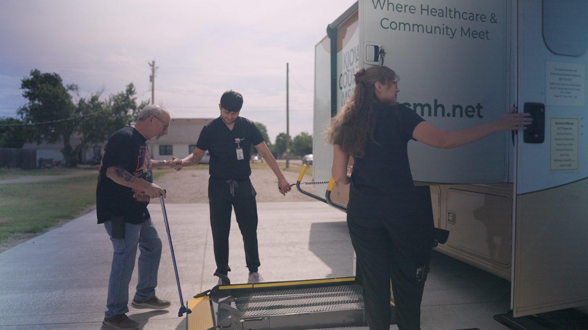 Clinical staff helping a patient onto the lift of a mobile health clinic